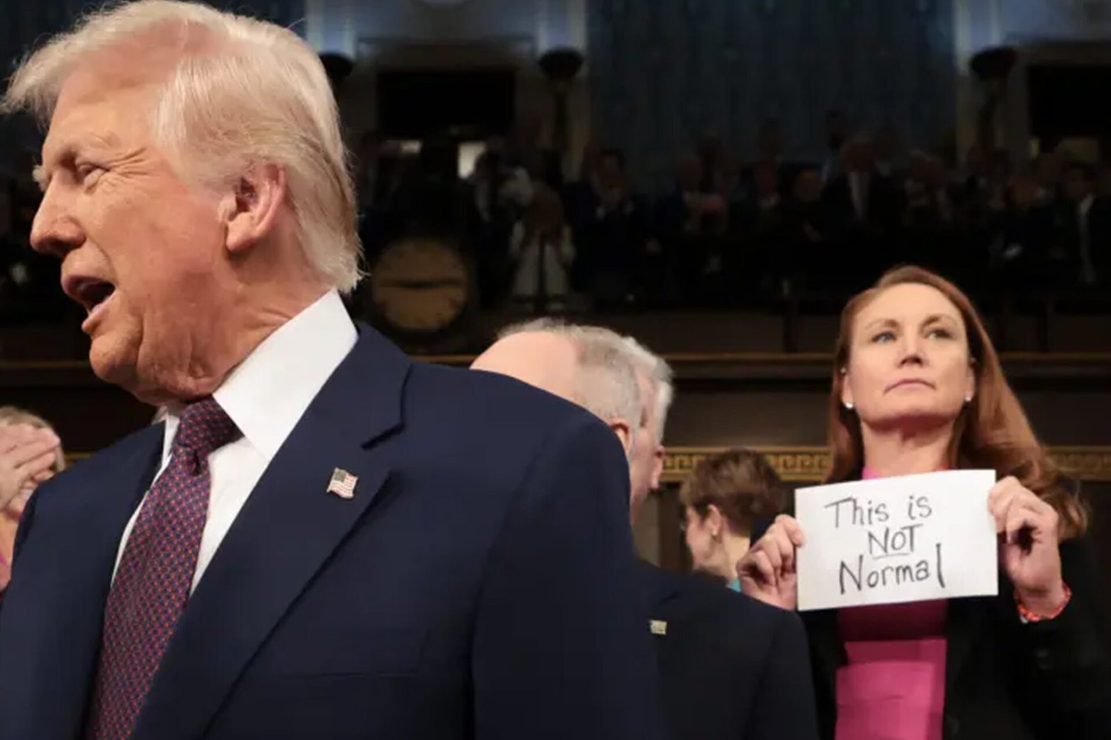 Dem holds up ‘This is not normal’ sign behind Trump as he enters, gets ...
